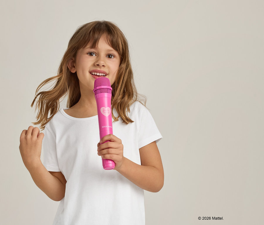 Mädchen im weißen T-Shirt hält ein pinkfarbenes Mikrofon.