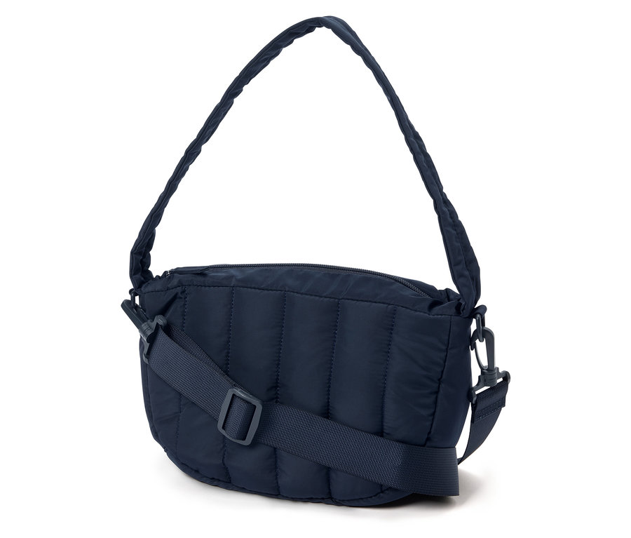 Eine marineblaue, gesteppte Handtasche mit einem verstellbaren Trageriemen liegt auf einem weißen Hintergrund.