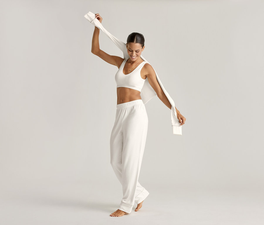 Frau im Pyjama-Set und Seamless-Bustier, creme, hält Oberteil hoch.