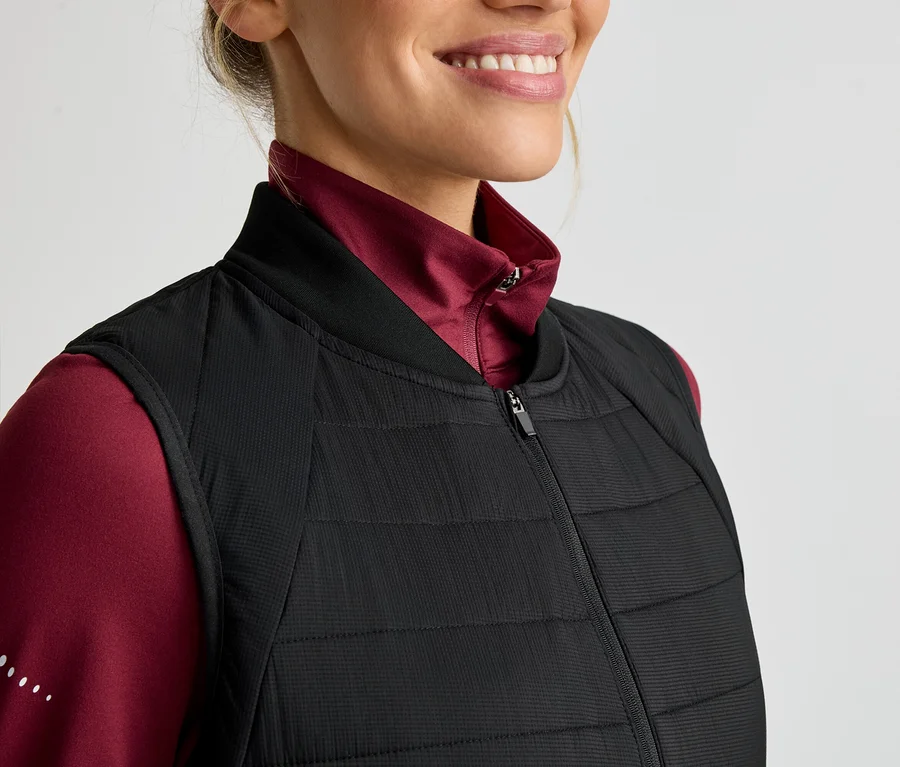Frau mit einem roten Langarmshirt und einer schwarzen, gesteppten Weste mit Reißverschluss.