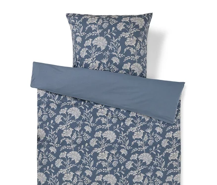 Ein blaues Bettwäscheset mit weißem Blumenmuster und passendem Kissenbezug, mit einem einfarbigen blauen Umschlag oben.