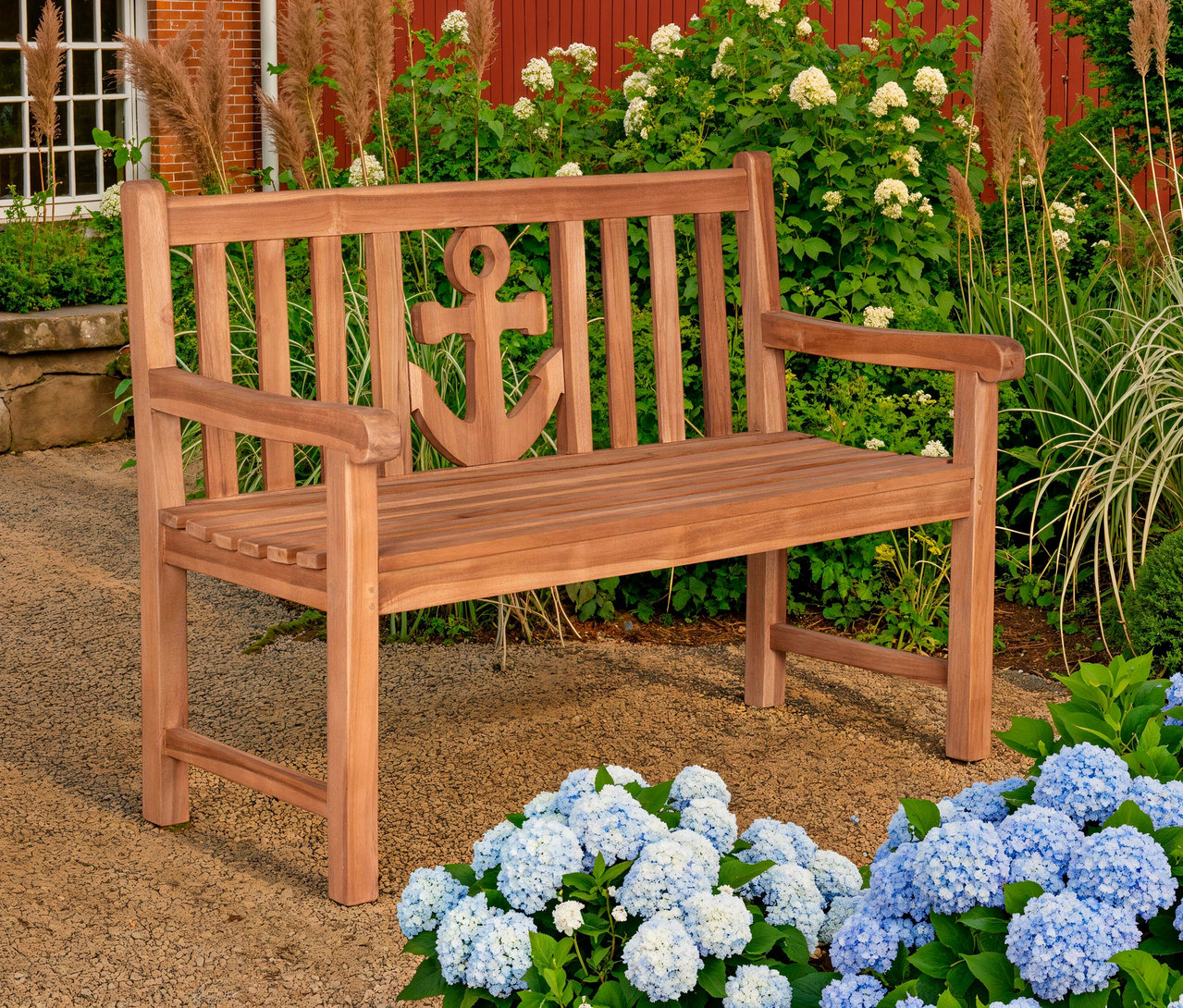 Eine deVries Gartenbank »Anker« steht im Garten, umgeben von Hortensien und Ziergräsern.