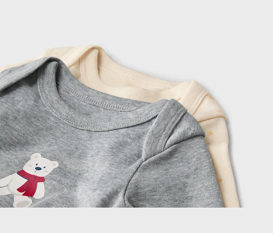 Zwei Baby-Bodys, ein grauer mit einem Eisbären-Aufdruck und ein cremefarbener mit Sternchen, liegen übereinander.