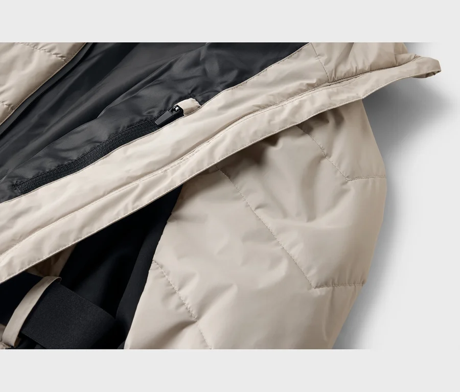Nahaufnahme einer beigen, gesteppten Jacke mit schwarzem Innenfutter und einem schwarzen Reißverschluss.