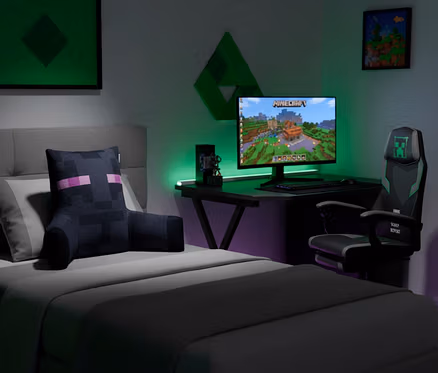 Schlafzimmer mit Gaming-Setup. Ein Bett mit Enderman-Kissen, ein Schreibtisch mit Minecraft-Monitor und ein Gaming-Stuhl mit Creeper-Logo. Grüne und violette Beleuchtung.