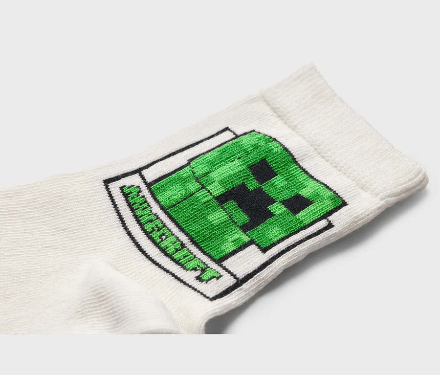 Nahaufnahme einer weißen Socke mit einem grünen Minecraft-Creeper-Motiv.