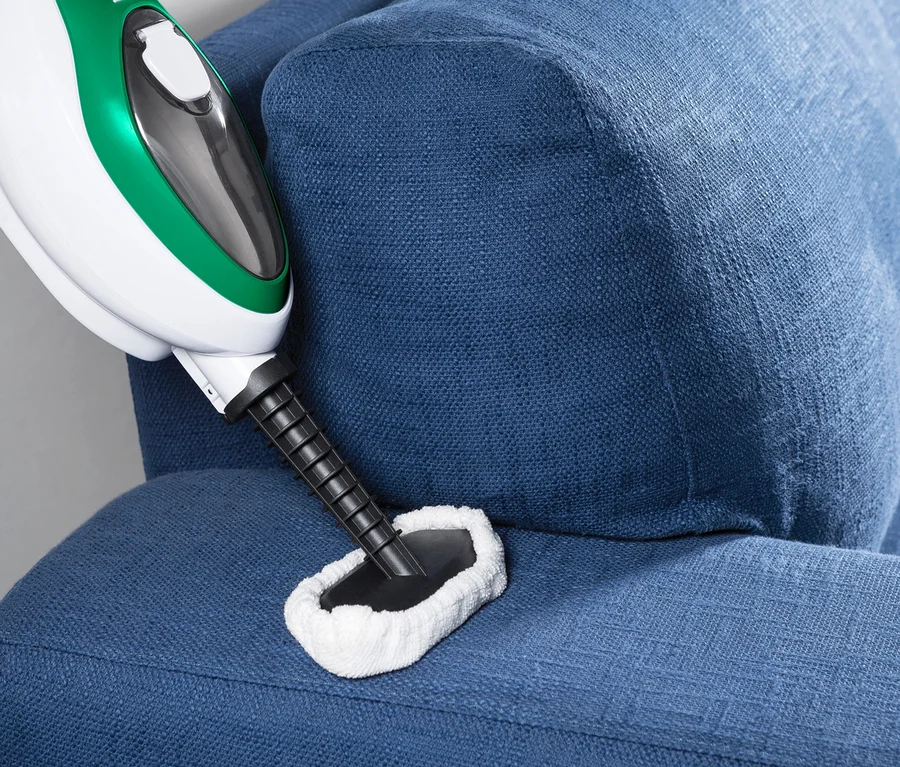 Detailaufnahme eines Multifunktionalen Dampfbesens auf einem blauen Sofa.
