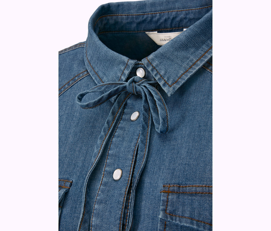 Detail einer Jeansbluse mit Knopfleiste und Bindeband.