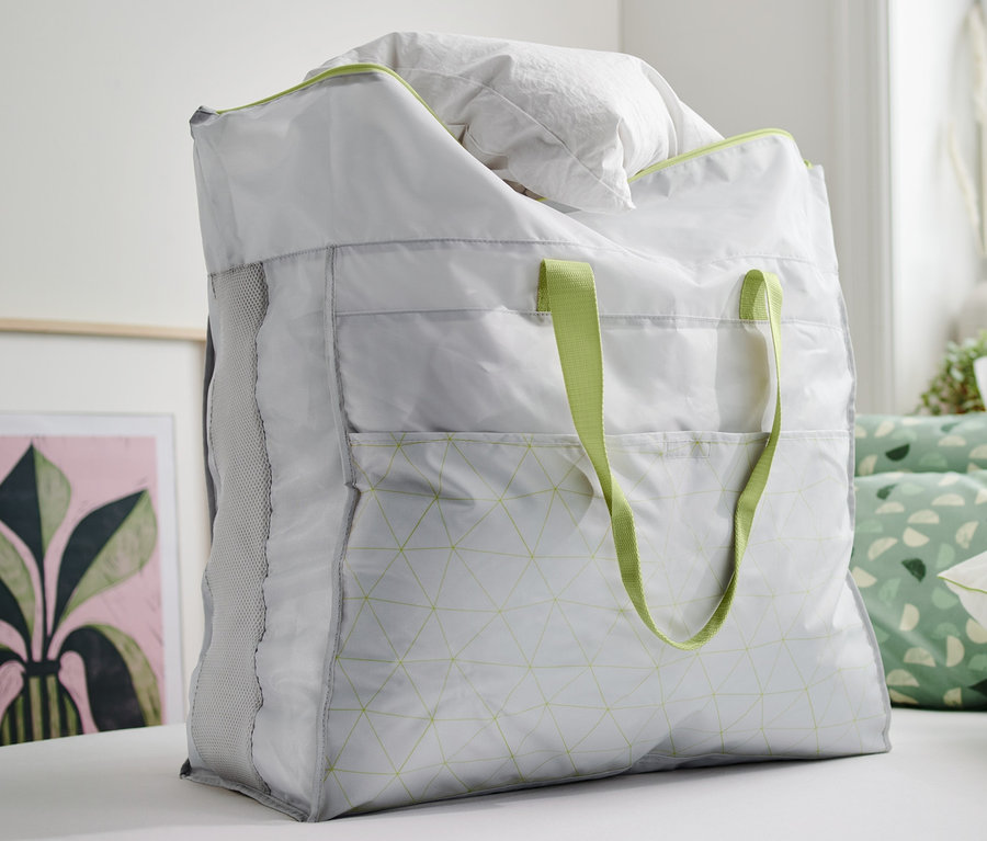 Eine Jumbo-Bettwarentasche gefüllt mit weisser Bettwäsche steht auf einem Bett.