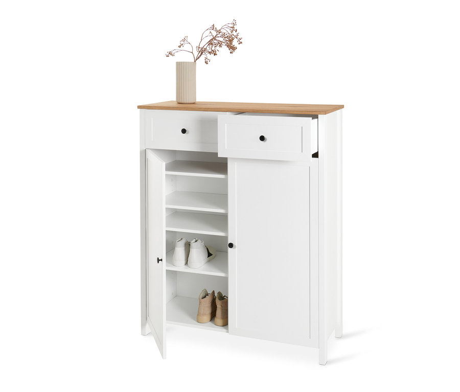 Weißer Schuhschrank mit Holzplatte, offener Tür und ausgezogener Schublade. Innen befinden sich Schuhe und oben eine Vase mit Pflanzen.
