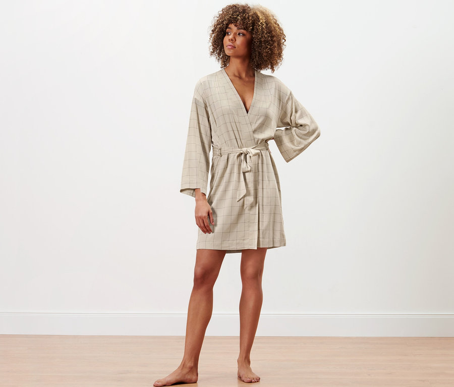 Frau steht und posiert in einem Morgenmantel.