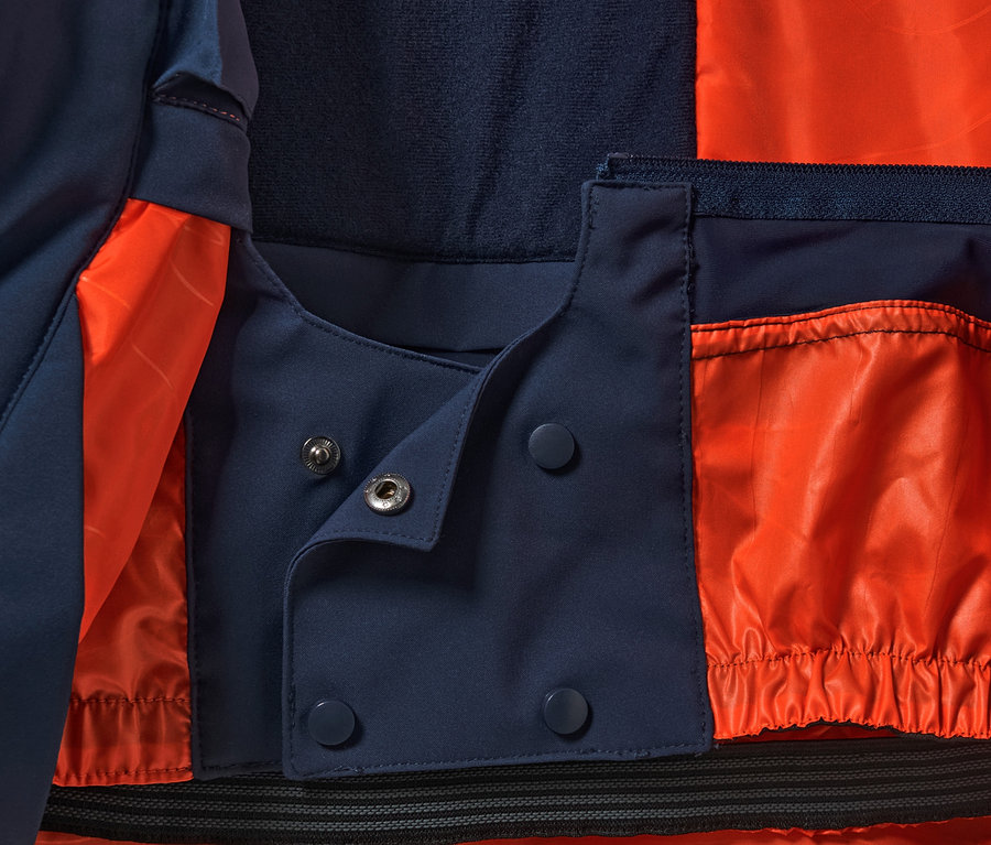 Detailansicht einer High-Tech-Skijacke mit orangefarbenem Futter und Druckknopfverschluss.