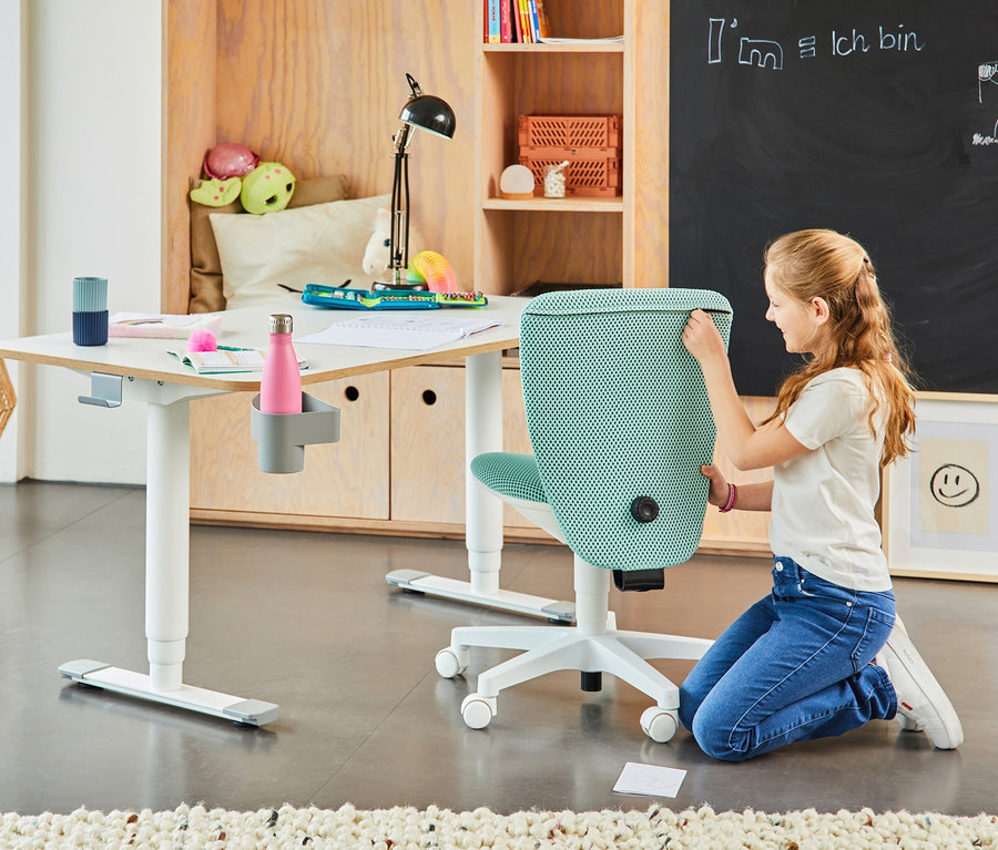 Mädchen kniet neben mintfarbenem Topstar Sitness »Home S'cool« Stuhl am Tisch.