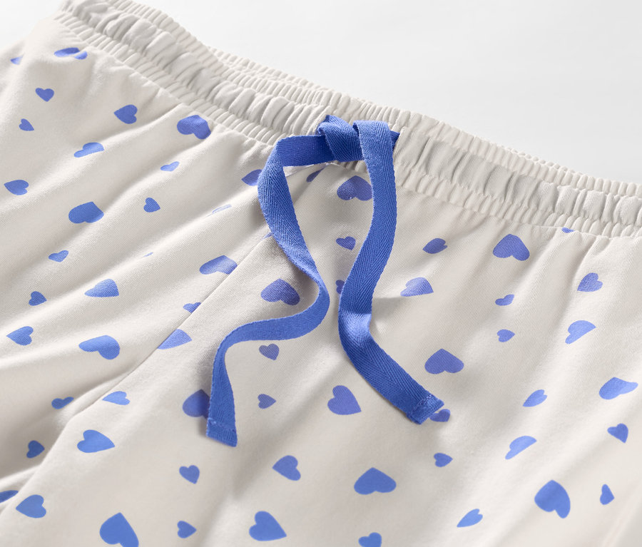 Detail einer Pyjamahose mit Herzen und blauem Band.