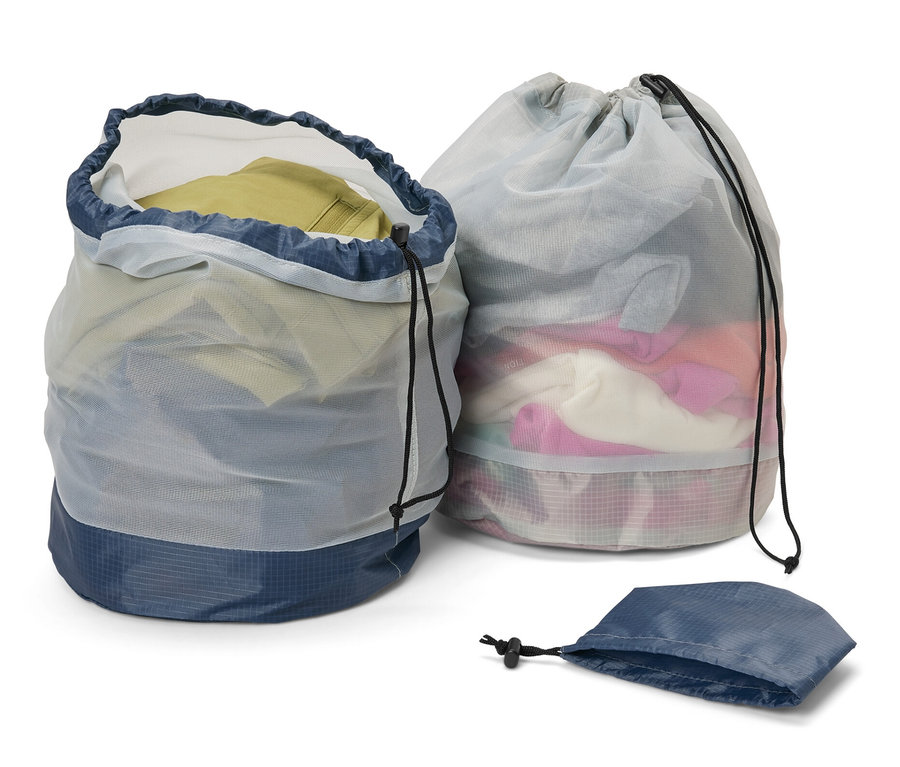 Zwei Outdoor-Meshbeutel, einer offen und mit Kleidung gefüllt, der andere geschlossen, sowie ein leerer Beutel.