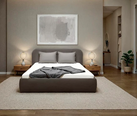 Schlafzimmer mit einem grauen Bett, grauen Kissen und einer grauen Decke auf einem weißen Bettlaken. Über dem Bett hängt ein Bild.