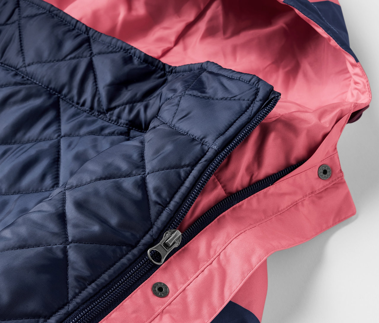 Detailansicht einer rosa-marineblauen 3-in-1-Regenjacke mit Kapuze.