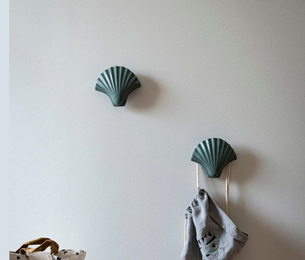 Zwei grüne »Shell« Haken an der Wand, an einem hängt ein grauer Beutel.