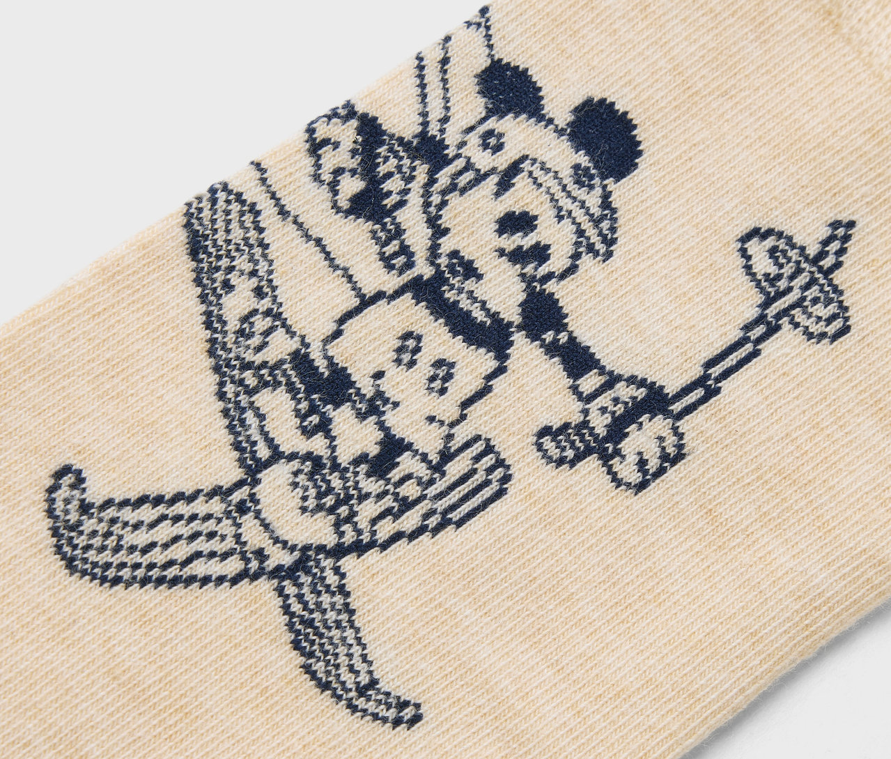 Detailaufnahme einer beigen Socke mit einem dunkelblauen Muster von Mickey Mouse beim Skifahren.