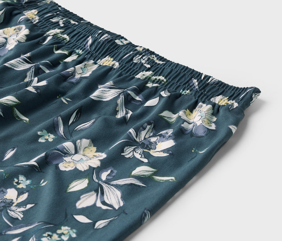 Detailaufnahme des elastischen Bundes und des Blumenmusters einer Hose.