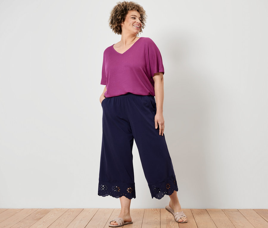 Frau posiert in einem strukturierten Shirt in Berry und einer Culotte mit Stickerei.