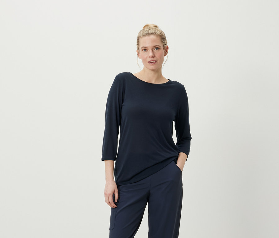 Frau posiert in marineblauem Dreiviertelarm-Shirt und Hose.