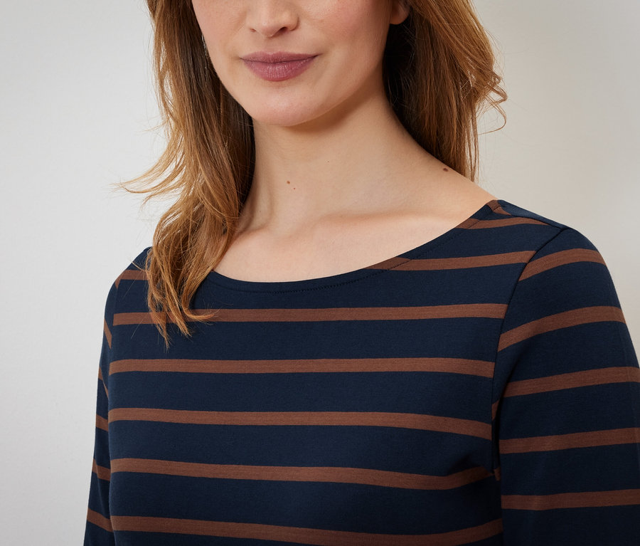 Oberkörper einer Frau in einem langärmeligen Streifenshirt.