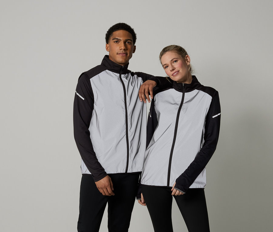 Mann und Frau posieren in langärmligen Jacken mit Reißverschluss.