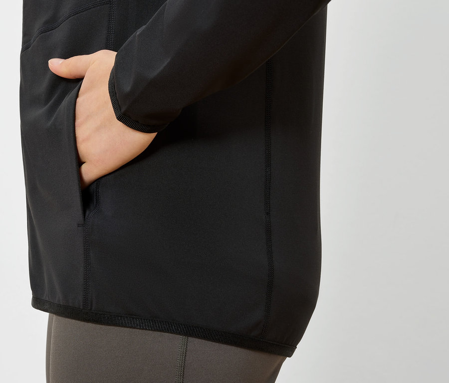 Hand in der Tasche einer schwarzen Jacke.