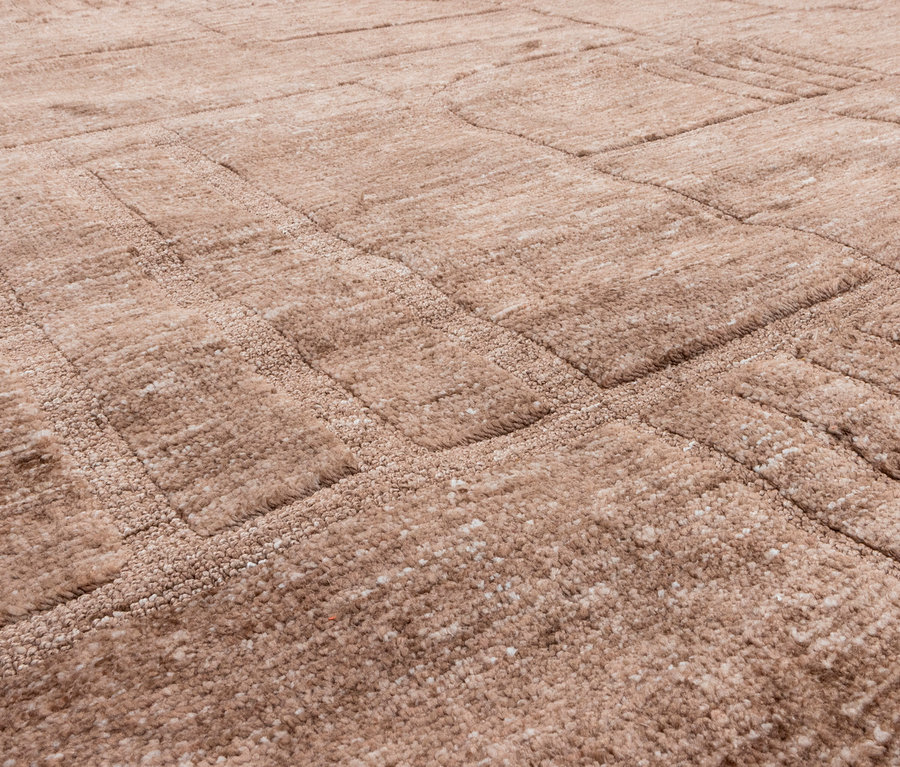Nahaufnahme eines beigen Teppichs mit erhabenem geometrischem Muster.