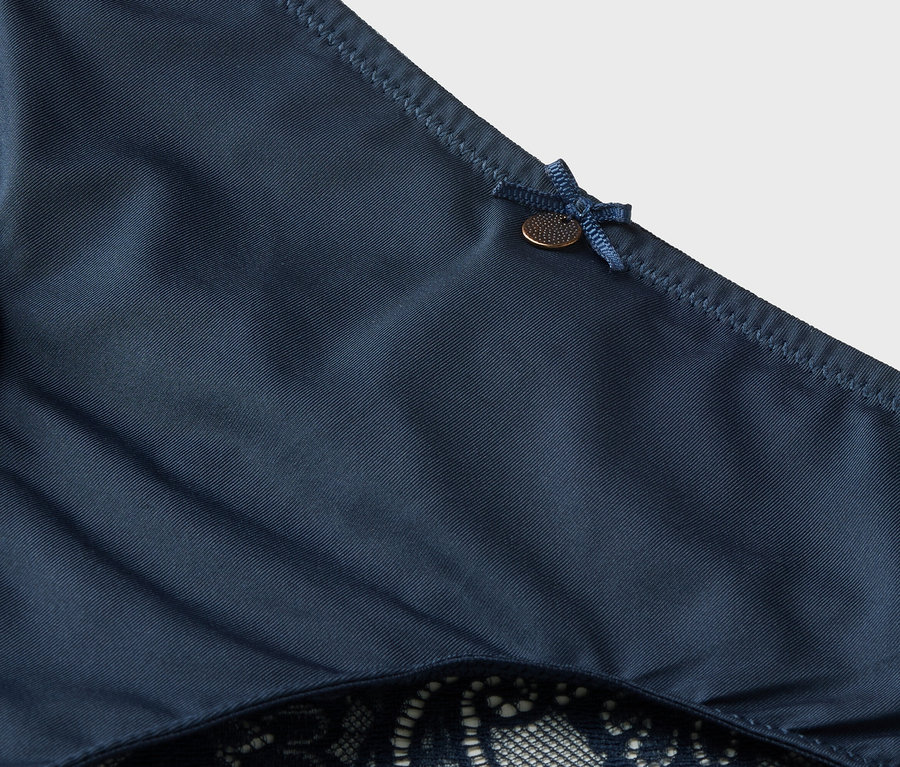 Detailaufnahme von dunkelblauem Slip mit Spitze und Schleife.