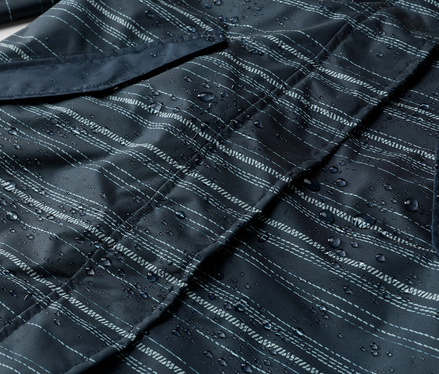 Nahaufnahme einer dunkelblauen, gestreiften Jacke mit Wassertropfen und einer Tasche.