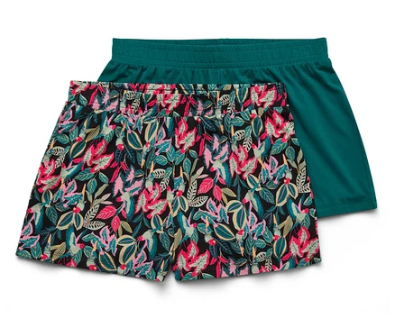 Zwei kurze Hosen liegen übereinander, eine mit Blumenmuster, die andere einfarbig grün.