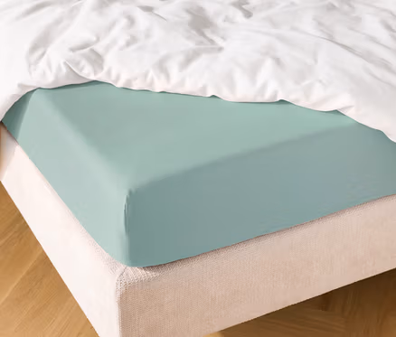 Bett mit hellblauem Spannbettlaken und weißer Bettdecke.