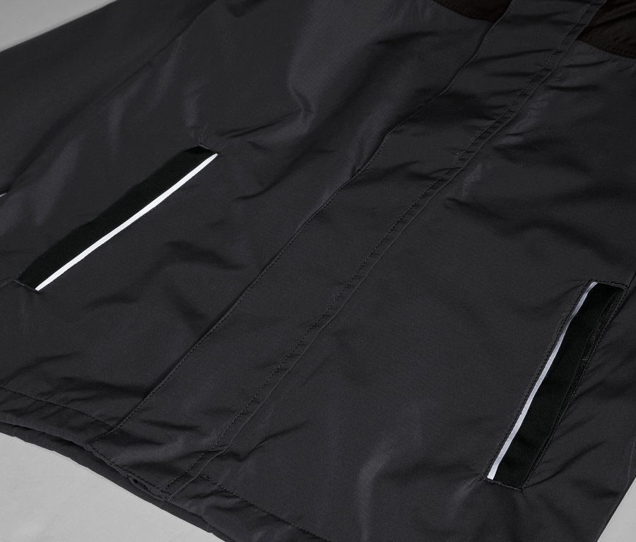 Nahaufnahme einer schwarzen Jacke mit Taschen, die mit einem reflektierenden Streifen versehen sind.