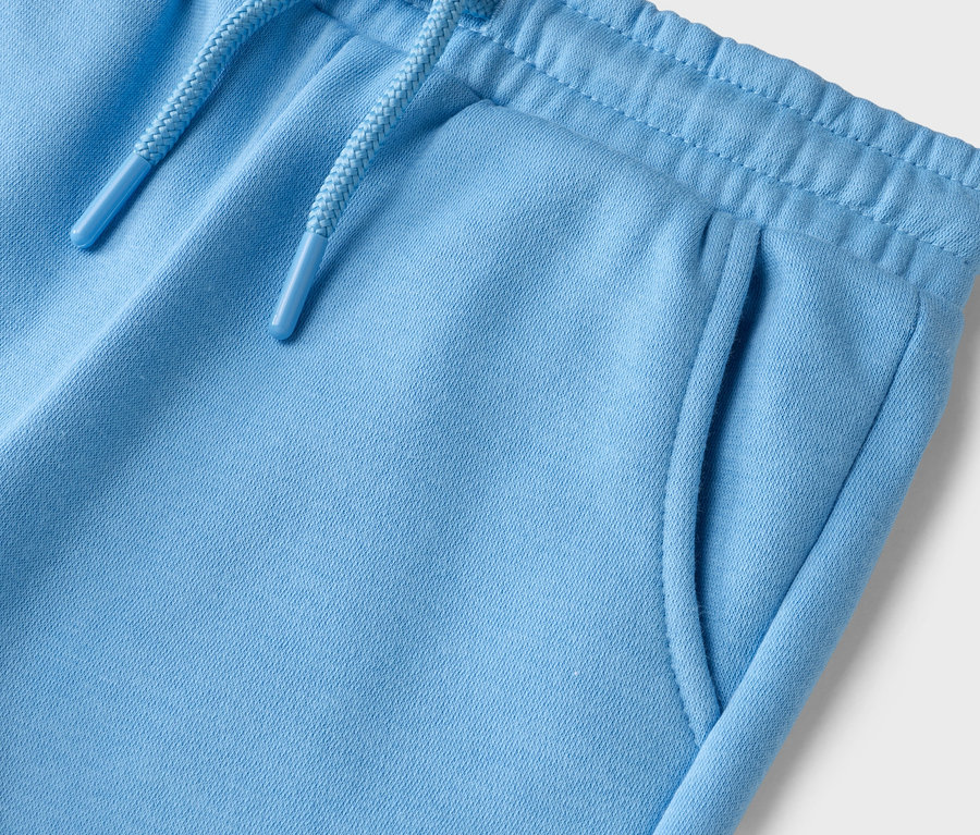 Nahaufnahme der Oberseite einer hellblauen Stoffhose mit Kordelzug und Taschen.
