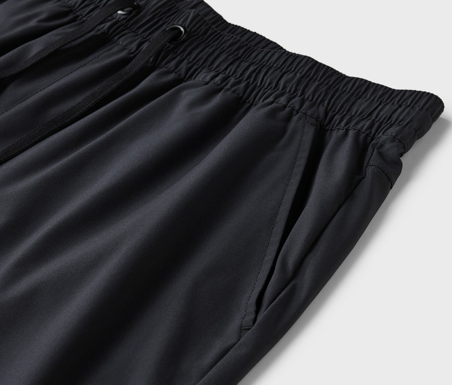 Detailaufnahme einer schwarzen Trainingshose mit elastischem Bund und Kordelzug.