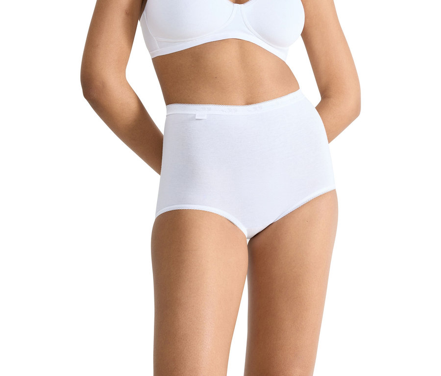 Frau trägt weiße Baumwollunterwäsche und einen BH, die Hände hinter dem Rücken verschränkt.