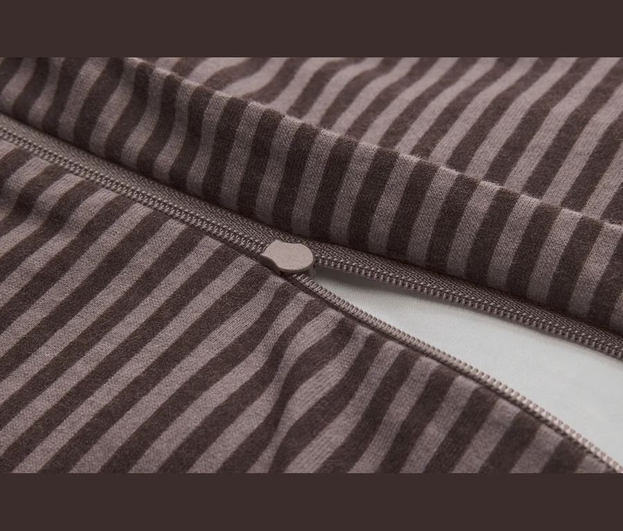 Nahaufnahme eines braun-beigefarbenen gestreiften Stoffes mit einem teilweise geöffneten Reißverschluss und sichtbarem Zipper.