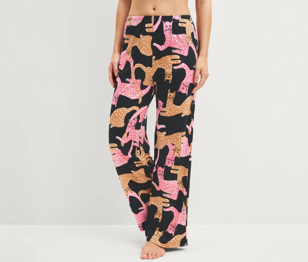 Frau trägt schwarze Hose mit rosa und braunen Katzenmustern.