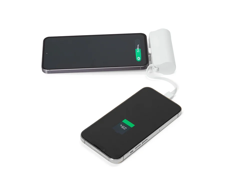 Zwei Smartphones, von denen eines mit einem weißen tragbaren Ladegerät verbunden ist, liegen auf einer weißen Oberfläche.