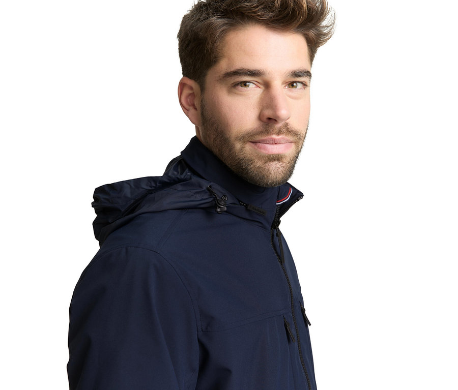 Mann trägt eine Tom Tailor Blouson-Jacke in Sky Captain Blue mit Kapuze.