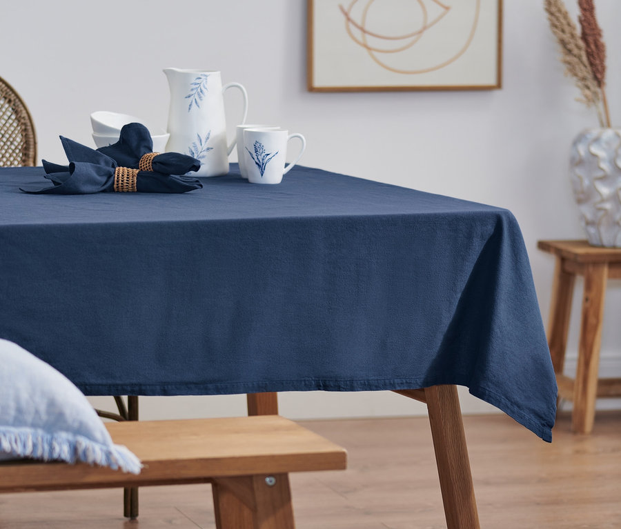Blauer Leinentischdecke, darauf Servietten, Krug und Tassen.