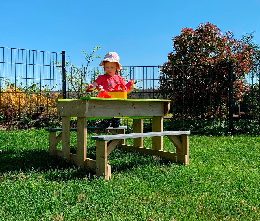 Ein Mädchen spielt am Wendi Picknick- und Matschtisch mit Bänken.