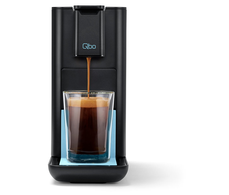 Kaffee fließt aus der Qbo ICONIC x Pantone Special Edition Sky Blue Kaffeemaschine in ein Glas.