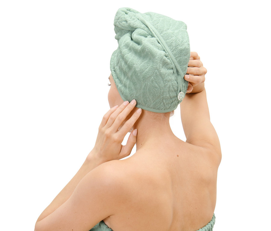 Frau befestigt ein Turban-Handtuch auf ihrem Kopf.