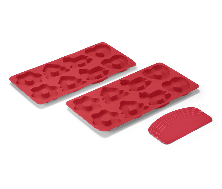 Zwei rote Mini-Lebkuchen-Backmatten und ein Schaber auf weißem Hintergrund.