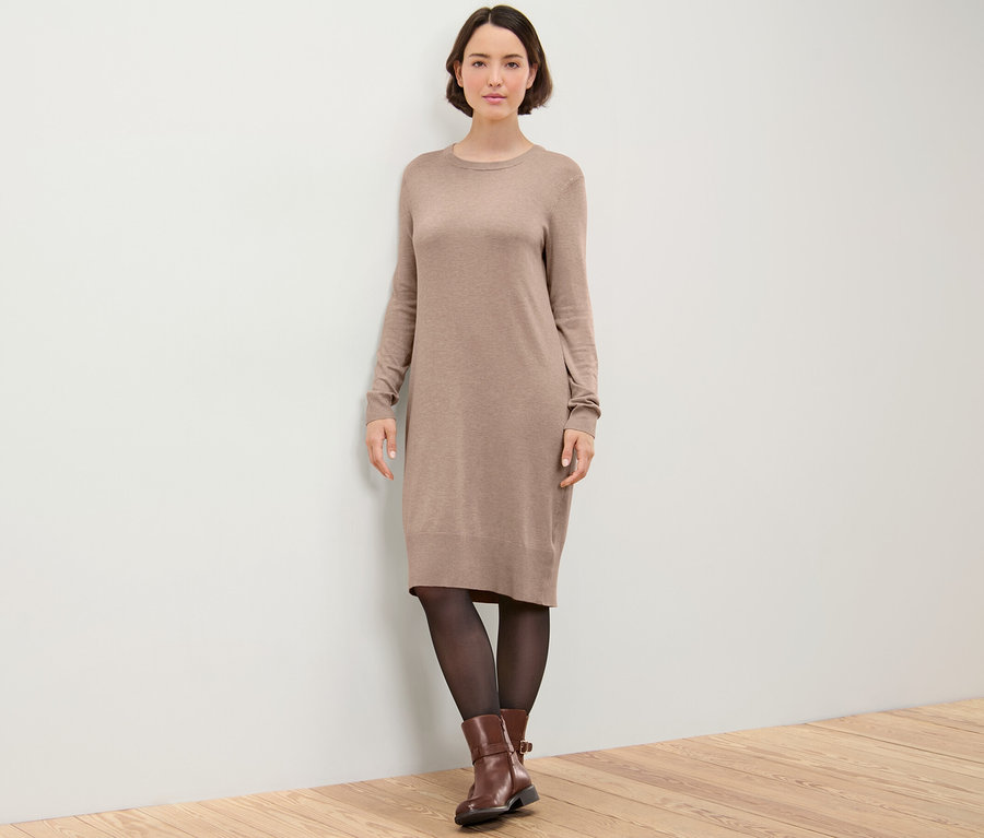 Frau posiert in einem braunen Feinstrickkleid.