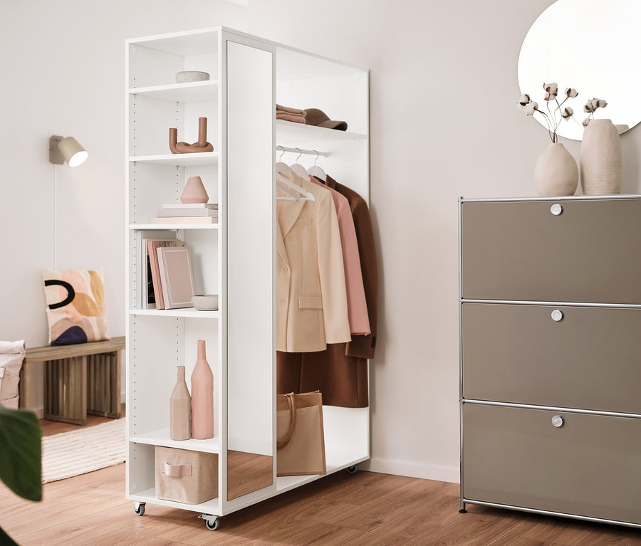 Einrichtung mit einer Ausziehbank, einer mobilen Spiegelschrank-Garderobe, einem Regal Metall »CN3« mit 3 Klappenfächern und einer cremefarbenen Wandleuchte aus Metall. Im Hintergrund hängt ein runder Spiegel »Ameca«.