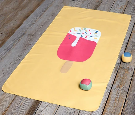 Ein gelbes Kinder-Microfaserhandtuch mit Eis liegt auf einem Holzboden.